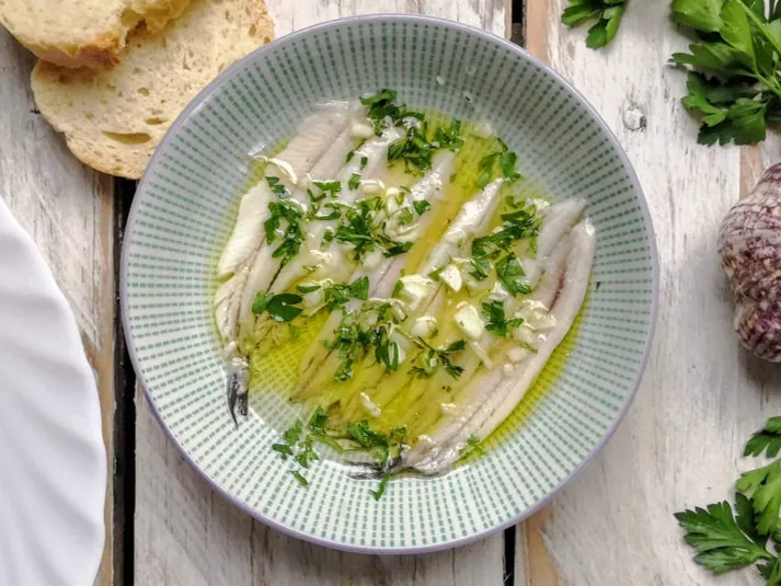 Boquerones en vinagre served with olive oil and parsley