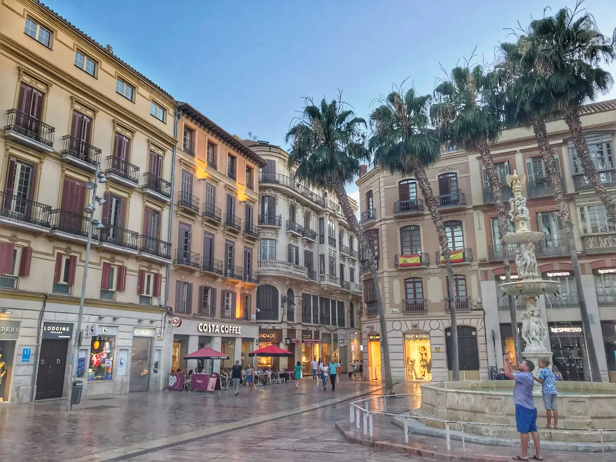 Evening in a central Malaga square with palm trees and terraces