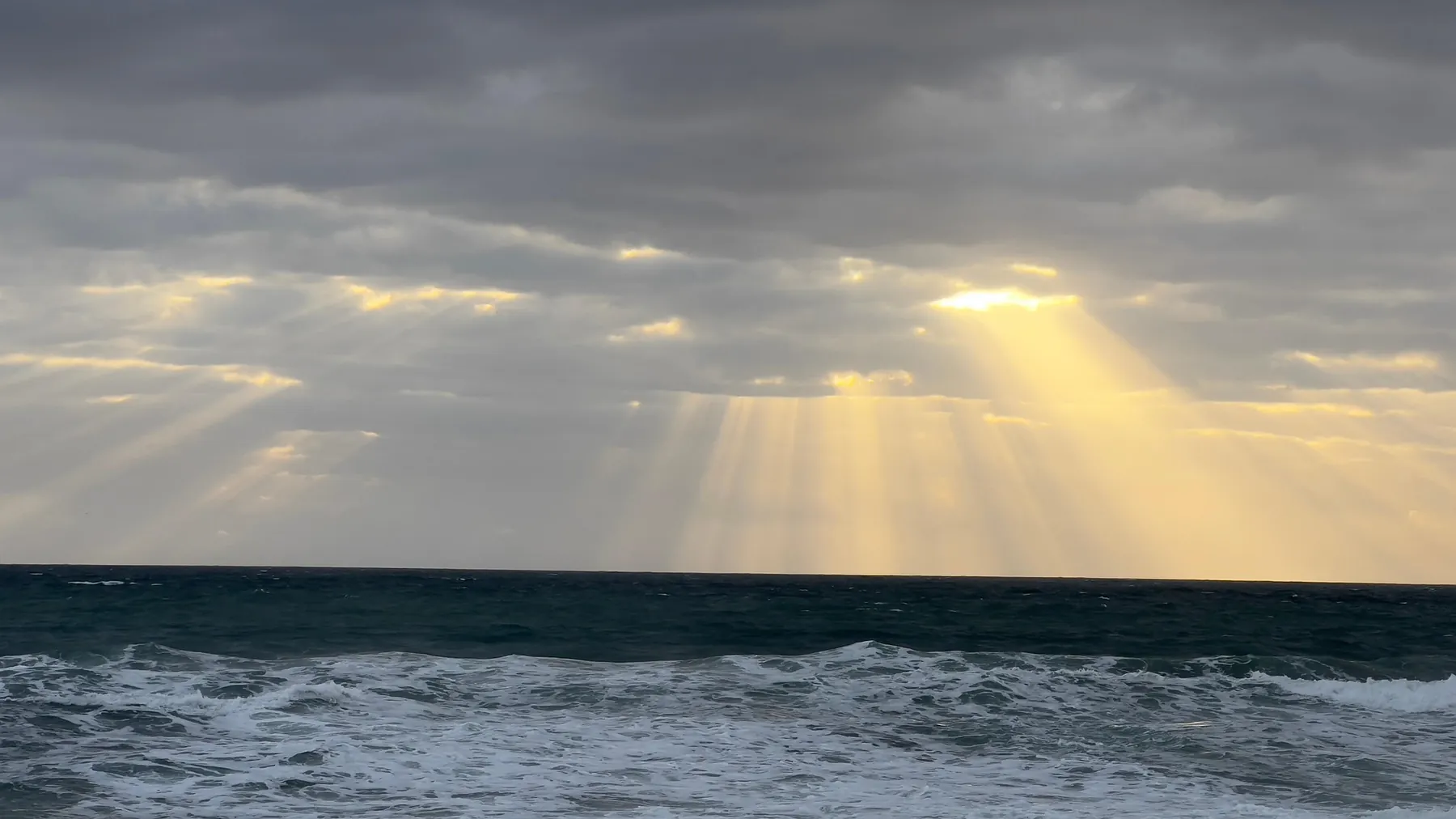Sunlight breaking through clouds over the Malaga coast
